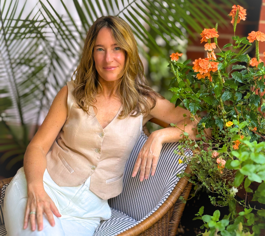 Woman sitting on a wicker chair with plants and flowers around her